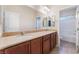 A bathroom featuring double sinks, a large mirror, and tile flooring, with an adjacent shower area, is shown at 6125 Paddleboat St, North Las Vegas, NV 89031