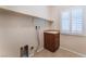 Convenient laundry room features tile flooring, built-in shelving, utility sink, and natural light from a window at 6125 Paddleboat St, North Las Vegas, NV 89031