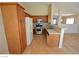 Functional kitchen with wood cabinets, white appliances, and tile countertops, adjacent to the living area at 7518 Luna Del Rey St, Las Vegas, NV 89123