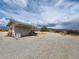 Desert property featuring a gravel driveway and small structure under a cloudy sky at 781 Buol Rd, Pahrump, NV 89048
