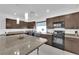 Well-lit kitchen with dark wood cabinets, black appliances, and granite countertops, offering ample space at 8178 Eaton Hill St, Las Vegas, NV 89113
