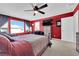 Stylish main bedroom featuring red accent wall, ceiling fan, dresser, and TV at 8178 Eaton Hill St, Las Vegas, NV 89113