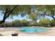 Community pool with a clear blue swimming area surrounded by a well-maintained deck, trees and a nearby lounging area at 8682 Gateway Glen Dr, Las Vegas, NV 89178