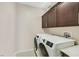 Well-lit laundry room with front loading washer and dryer and dark wood cabinets at 881 Barrhead Ave, Henderson, NV 89012