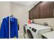 Bright laundry room with front-load washer/dryer, dark cabinets, and clothing rack at 881 Barrhead Ave, Henderson, NV 89012