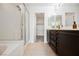 Bright bathroom featuring a shower, tub, and double vanity with dark cabinets and tile flooring at 9545 Parker Springs Ct, Las Vegas, NV 89166