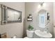 Updated powder room with decorative mirror, pedestal sink, toilet, and neutral paint color at 10404 Stanberry Ave, Las Vegas, NV 89135
