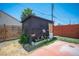Backyard shed featuring a wooden door and shelves, surrounded by greenery and a modern fence at 108 Verdy Ln, Las Vegas, NV 89101