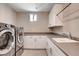 Well-lit laundry room boasts modern washer and dryer, storage cabinets and plenty of countertop workspace at 10985 Limeslice Ave # 2, Las Vegas, NV 89135