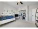Neutral toned bedroom featuring a daybed with blue pillows, ceiling fan, TV and a desk and closet area at 1321 Hudson Creek Pl, North Las Vegas, NV 89084
