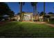 Well-maintained single-story home with a sprawling front lawn and mature palm trees, enhanced by exterior lighting at 2231 S Tioga Way, Las Vegas, NV 89117