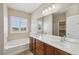 Bathroom with double vanity, large mirror, and soaking tub near a window with shutters at 2284 Carambala Ln, Henderson, NV 89044