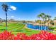 Scenic golf course view with water feature and mountain backdrop, framed by red flowers at 236 Dog Leg Dr, Las Vegas, NV 89148