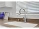 Close up of a kitchen sink that includes a chrome faucet, white basin, neutral countertops, and bottles in front of the window at 236 Dog Leg Dr, Las Vegas, NV 89148