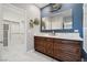 Modern bathroom featuring double sinks, a large mirror, and a walk-in closet for ample storage at 2425 Sturrock Dr, Henderson, NV 89044