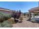 Desert-landscaped backyard with a covered patio and wrought-iron fencing at 2538 Capella Star St, Henderson, NV 89044