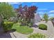 Landscaped backyard with lush greenery, decorative rock, and a variety of trees providing shade and privacy at 2601 Harrisburg Ave, Henderson, NV 89052