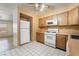 Kitchen with wooden cabinets, white appliances, tile flooring, and lots of light at 411 Monmouth Ct, Henderson, NV 89015