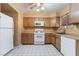 Well-lit kitchen featuring wooden cabinets, white appliances, and white tile flooring at 411 Monmouth Ct, Henderson, NV 89015