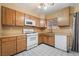 Kitchen with wood cabinetry, white appliances, and a window view at 411 Monmouth Ct, Henderson, NV 89015
