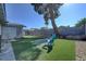 A backyard featuring artificial turf, a large shade tree, and a block fence at 4445 Peterson Dr, Las Vegas, NV 89103