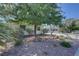 A cozy single-story home featuring low-maintenance gravel landscaping and mature trees in the front yard at 4445 Peterson Dr, Las Vegas, NV 89103