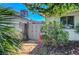 A view of the side yard with a decorative gate with mature vegetation and palm trees at 4445 Peterson Dr, Las Vegas, NV 89103