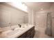 Bright bathroom featuring double sinks, framed mirrors, a shower-tub combo, and white tile at 4652 Wyncrest Ave, Las Vegas, NV 89115