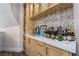 Close-up of the wet bar featuring light wood cabinetry, white countertops, backsplash, and a variety of beverages at 5186 San Milano Ave, Las Vegas, NV 89141