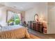 Bright bedroom featuring a decorative wrought iron bed frame, dark wood floors and backyard views through sheer curtains at 5186 San Milano Ave, Las Vegas, NV 89141
