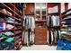Spacious walk-in closet with custom shelving, hanging rods, drawers, and glass-door cabinets for optimal organization at 5186 San Milano Ave, Las Vegas, NV 89141