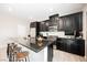 Modern kitchen featuring dark cabinetry, granite countertops, and bar stool seating at 7002 Fossil Rim St, North Las Vegas, NV 89084