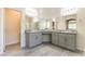 Bright bathroom featuring dual sink vanity, large mirror, and stylish gray cabinets at 7265 Southern Magnolia St, Las Vegas, NV 89149