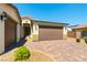Close-up of the front of the house showing a two-car garage with a brick-paved driveway and desert landscaping at 7265 Southern Magnolia St, Las Vegas, NV 89149