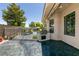 Backyard patio with built-in outdoor kitchen, wrought iron pool fence, and manicured landscaping at 7718 Willow Cove Cir, Las Vegas, NV 89129