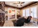 Library with bookshelves, a ceiling fan, comfortable seating, and natural light from shuttered windows at 7718 Willow Cove Cir, Las Vegas, NV 89129