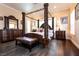 Main bedroom with dark wood floors and a four-poster bed with a seating bench at the foot at 7718 Willow Cove Cir, Las Vegas, NV 89129