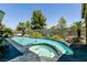 Beautiful in-ground pool with unique design and surrounded by lush greenery under a blue sky at 7718 Willow Cove Cir, Las Vegas, NV 89129