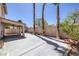 A wide, paved backyard featuring a covered patio, privacy wall, and mature palm trees at 829 Dancing Vines Ave, Las Vegas, NV 89183