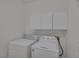 Well-lit laundry room features a full-size washer and dryer with storage cabinets above at 829 Dancing Vines Ave, Las Vegas, NV 89183