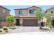Two-story home features a desert landscape, a brick driveway, and a two-car garage at 871 Aurelie Ridge St, Henderson, NV 89011