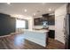 Open-concept kitchen with dark cabinets, stainless steel appliances, a large island, and wood-look floors at 871 Aurelie Ridge St, Henderson, NV 89011