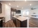 Open-concept kitchen with a large island, stainless steel appliances, dark cabinets, and wood-look floors at 871 Aurelie Ridge St, Henderson, NV 89011