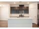 Bright kitchen features dark cabinets, stainless steel appliances, a large island, and sleek, modern lighting at 871 Aurelie Ridge St, Henderson, NV 89011