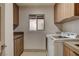 Functional laundry room with modern washer and dryer, wooden cabinets, and a frosted window at 9921 Mirada Dr, Las Vegas, NV 89144