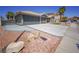 Wide driveway leading to a two-car garage, complemented by desert landscaping and mature palm trees at 1519 Deerford Cir, Las Vegas, NV 89110