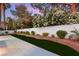 Lush backyard with a concrete patio, artificial turf, and a privacy wall adorned with colorful plants at 1616 Shadow Rock Dr, Las Vegas, NV 89117