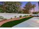 Lush backyard with a concrete patio, artificial turf, and a privacy wall adorned with colorful plants at 1616 Shadow Rock Dr, Las Vegas, NV 89117