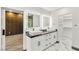 Bright bathroom featuring double sinks, illuminated mirrors, dark countertops, and a walk-in closet at 1616 Shadow Rock Dr, Las Vegas, NV 89117