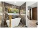 Stunning bathroom with marble accents, a modern freestanding tub, and a view of lush greenery at 1616 Shadow Rock Dr, Las Vegas, NV 89117